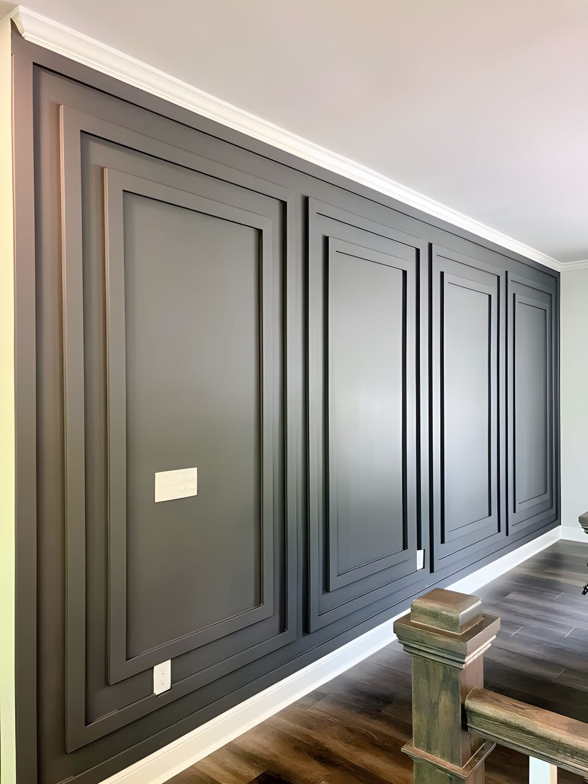 Dark gray accent wall with raised panels in a modern home, perfect for custom wallpaper installations.