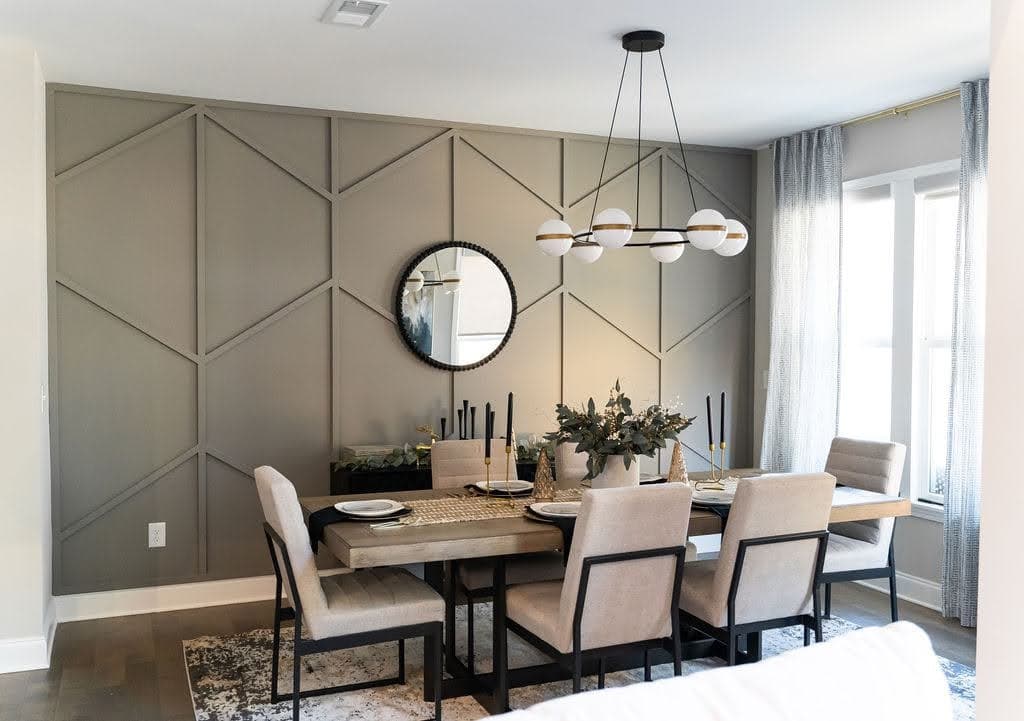 Dining room with gray geometric accent wall paneling, a circular mirror, and modern chandelier.